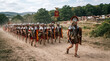 © Argiduna - Una legión de soldados romanos con armadura, escudos y estandartes marcha en formación por un camino de tierra junto a un fuerte de madera.