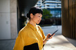 © Davor - Professional woman using smartphone outdoors in city