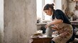© AdPremium - Young woman potter shaping a wet clay vase on a spinning pottery wheel in a bright rustic ceramic workshop
