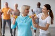 © Prostock-studio - Smiling Elderly Caucasian Woman Engaged In Fitness Activity With Dumbbells While Receiving Guidance From Young Female Trainer At Gym. Promoting Active Lifestyle Among Seniors.