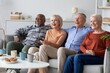© Prostock-studio - Smiling Group Of Four Senior Friends, Two Male And Two Female, Enjoying Each Other's Company While Watching Tv Together In Living Room, Relaxed Atmosphere Amongst Friends At Home. Friendship Concept.