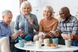 © Prostock-studio - Smiling Senior Caucasian Group Of Five Playing Cards Together In Cozy Living Room At Home, Enjoying Each Other's Company And Bonding Over A Fun Card Game, Celebrating Friendship And Laughter.