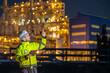 © BESTIMAGE - Inspector worker inspecting petroleum engineering in oil refinery performance checklist inspection at fuel industrial plant Male engineer pointing up and using tablet at site during night time
