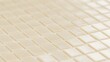 © Bussakon - Close up of cream colored square tiles arranged in a neat grid pattern with soft lighting and shallow depth of field