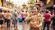 © kerkpun - A happy Thai woman splashing water from a traditional brass bowl with colorful flowers during the Songkran water festival. Sunny summer day with a blurred background of people celebrating Thai New Yea