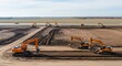© Tan - Multiple yellow excavators actively working and shaping the ground at a large construction site under a bright sky.