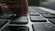 © InfiniteFlow - A close view of a finger typing on a laptop keyboard, featuring overlaying lines of code and programming language, symbolizing modern technology and software development. Xenic
