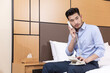 © HuaThuy - Businessman talking on hotel room phone while sitting on bed