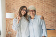 © Daniel - Smiling mother and adult daughter embracing at home against a brick wall, casual family portrait