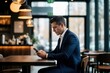© Maryna - Man in suit uses smartphone at cafe table. Pro checks mobile device while sitting indoors. Person works remotely in modern restaurant with coffee.