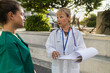 © PintoArt - Healthcare professionals discussing patient care outside hospital building