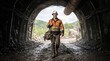 © Mirzasafwan - Miner walking through dark underground tunnel with safety gear.