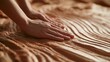 © Anat art - Hands mold wet clay into soft grooves while working on a textured surface. The setting shows an artisanal craft environment.