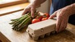 © ศิวาพร ทูปคันโธ - A person's hands place a carton of eggs next to fresh asparagus and ripe tomatoes on a wooden table
