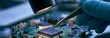 © tongpatong - Placing a chip on a circuit board under a magnifying lamp with tweezers while wearing gloves