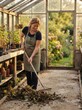 © Bohdan - Woman tending to her lush greenhouse sanctuary raking fallen leaves with gentle care in the warm golden glow of a peaceful afternoon retreat