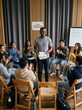 © Ariestia - Smiling African American Mentor Leading a Youth Empowerment Workshop with a Diverse Group of Students Clapping in a Circle