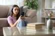 © PheelingsMedia - Serious woman checking smartphone in the living room