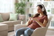 © PheelingsMedia - Serious woman wearing headphone checking playlist on phone