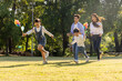 © comzeal - Happy Asian family with parents and kids running together on green grass field in sunny park, holding colorful pinwheels during summer outdoor vacation, enjoying leisure leisure time and bonding