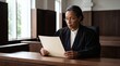 © Azorahaiá - Experienced female judge in judicial robe reading legal documents in courtroom with wooden benches and large windows