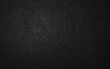 © Putu - Dark black textured paper background or charcoal gray surface with fine grain.