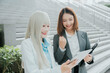 © JK_kyoto - Happy teamwork business people working together on digital tablet with joyful emotion and professional attire on an outdoor stair