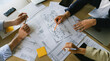 © mrzn - Business team reviewing architectural blueprints together on a wooden table in office with architecture