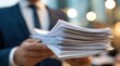 © dmmarychev - Businessperson holding large stack of white documents