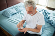© Davor - Senior man taking medication on bed at home