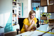 © Davor - Young woman eating healthy lunch while working on laptop in modern office