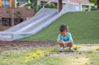 © leungchopan - Toddler squatting on ground near playground slide outdoors