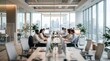 © Chayanan - Employees working in a bright modern office environment with large windows and overhead lighting.