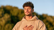 © OHMAl2T - Young man outdoors meditating with eyes closed and hand on chest
