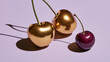 © stock by siam - Two golden metallic cherries and one natural dark cherry rest on a sleek purple surface with sharp shadows. This unique luxury food concept is ideal for gourmet design projects.