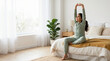 © OlgaNeuroArt - Young girl in pajamas stretching her arms while sitting on a bed. Child waking up and doing a morning stretch in a bright bedroom