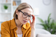 © Liubomir - Woman wearing glasses feeling strong pain and discomfort from a headache, migraine or stress, touching her temple while suffering at home or in the office