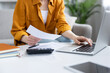 © Liubomir - Woman reviewing bills and receipts while calculating expenses on a laptop and calculator in a comfortable home office, managing personal finances and remote work productivity