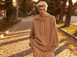 © ON - Studio - Beautiful young woman with short blonde hair wearing oversized knitted sweater posing in autumn park. Fall fashion style and cozy seasonal outfit concept. Street fashion portrait at golden hour.