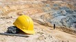 © pufanya - Yellow safety hardhat and coal sample on cracked ground. Metal survey stake in an open pit mine. Mining industry and geological exploration concept