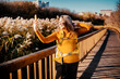 © 5ph - Playful woman on autumn hike taking selfie photo with mobile phone - content creation. Cheerful female traveler posing for social network outdoor. Digital lifestyle and vanity concept.
