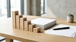 © rezaul4022 - Wooden blocks forming a decreasing bar chart with downward arrows on a modern office desk