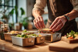 © Krystsina - Close-up of a man's hands packing a lunch box for work