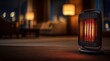 © Taiwo - Black electric radiant patio table heater with a glowing orange heating element inside a protective wire mesh guard.