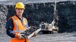 © Sergei - Industrial miner holding a tray of black coal at an open-cast mine. Worker in yellow helmet and orange safety vest displaying coal sample