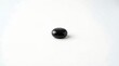 © Lucas - A sleek black stone sits alone on a pristine white surface