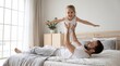 © Eka - Happy father lifting excited daughter pretending to fly playing on bed at home