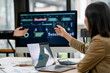© amnaj - Business people discussing data visualizations on a monitor, analyzing financial charts and reports to develop a strategic plan