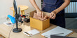 © Natee Meepian - Cropped Hands Packing Product into Cardboard Box for E-Commerce Order Fulfillment