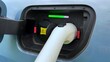 © NBLX - Charging port on electric vehicle with connected cable and colored indicator lights showing status